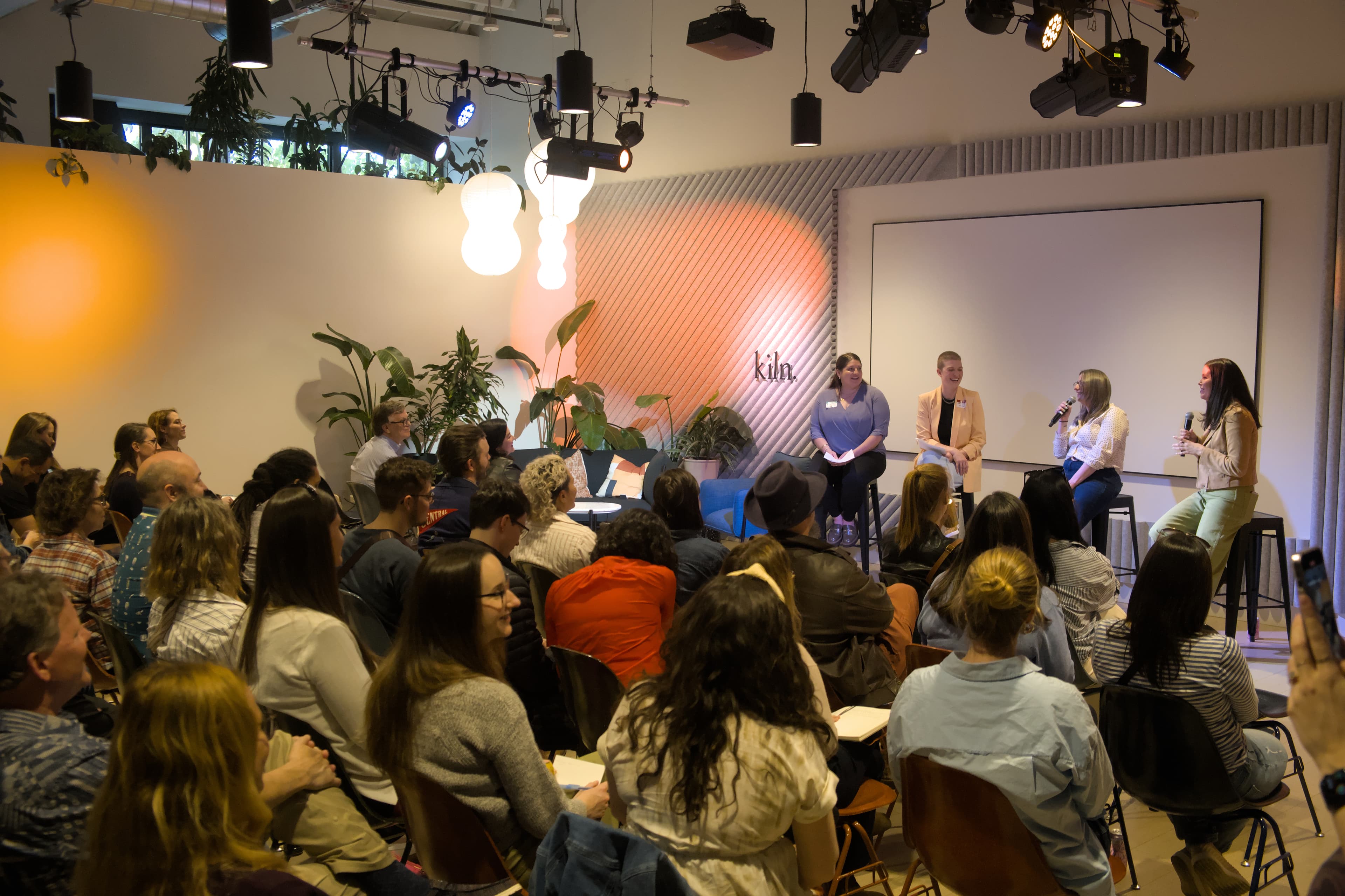 A panel discussion in front of a warm-lit Kiln backdrop
