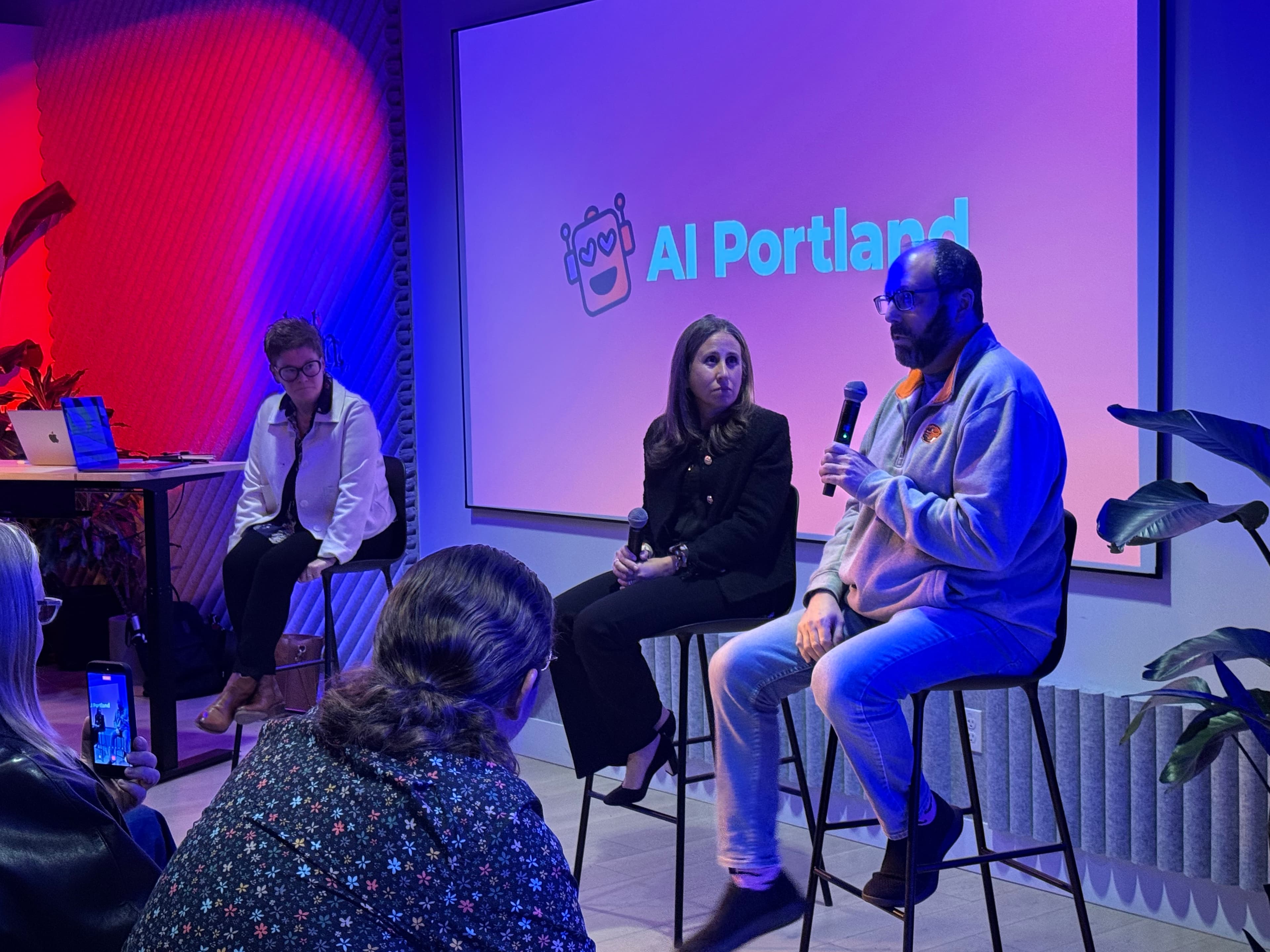 A panel discussion in front of the AI Portland logo